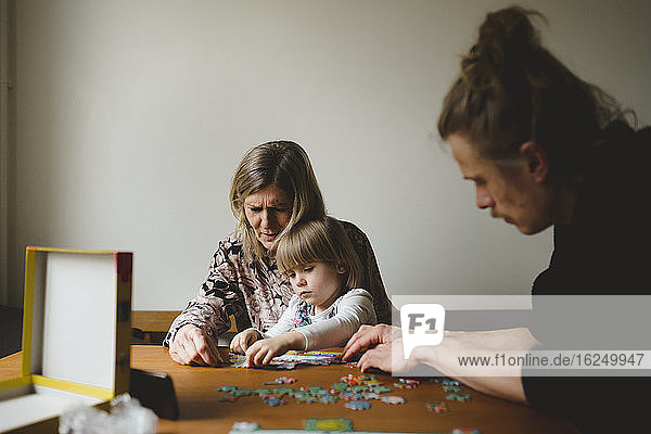 Großeltern und Enkelin beim Puzzeln