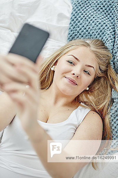 Frau im Bett nimmt Selfie
