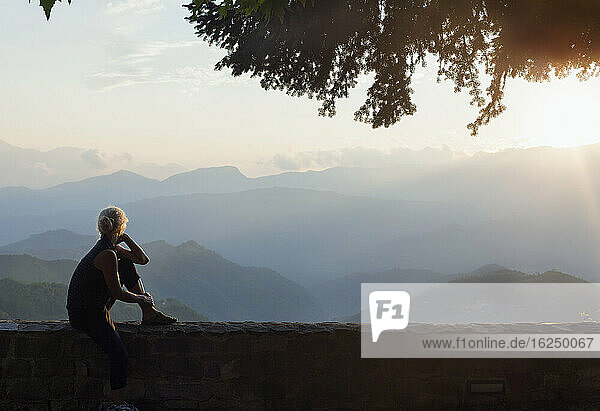 Frau sitzt und blickt auf die Berge