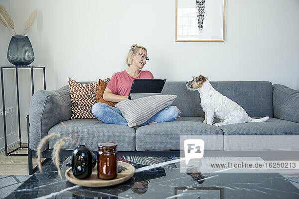 Woman on sitting on sofa with dog