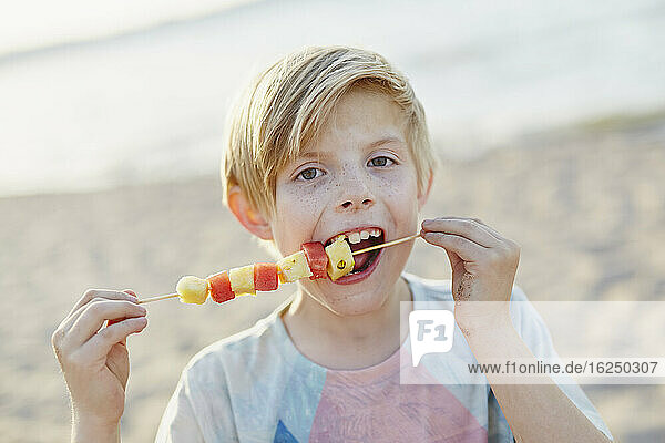 Boy eating fruit kebab