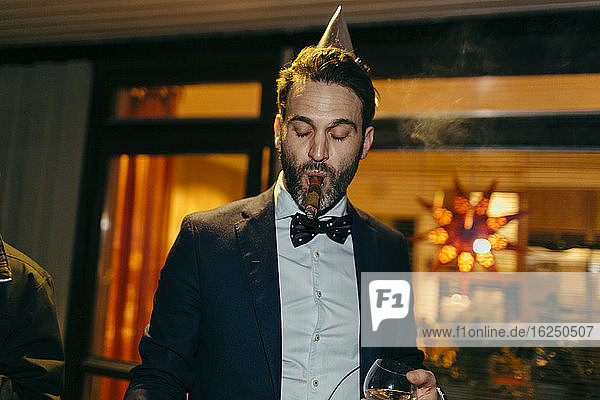 Mann raucht Zigarre auf einer Party
