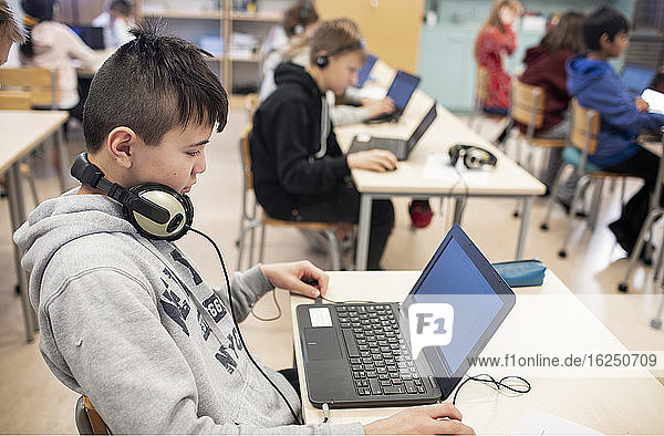Boy in classroom using laptop