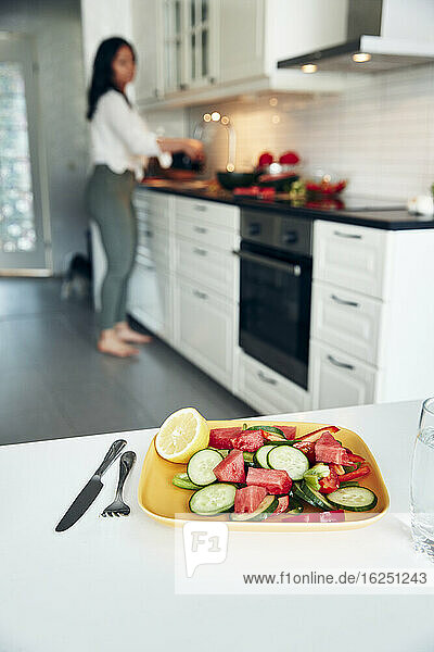 Salat auf einem Teller  Frau in der Küche im Hintergrund