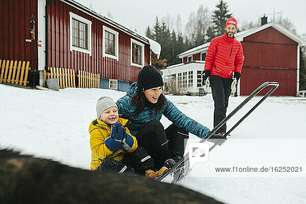 Mother with son on sleigh snow shovel