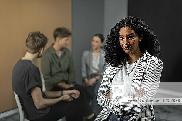 Frau schaut in die Kamera  im Hintergrund Mitarbeiter bei einer Besprechung