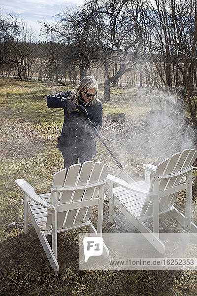Woman cleaning chairs in garden