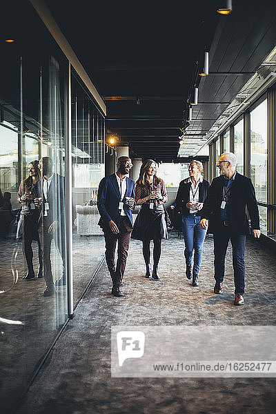 Smiling female and male entrepreneurs walking in office corridor