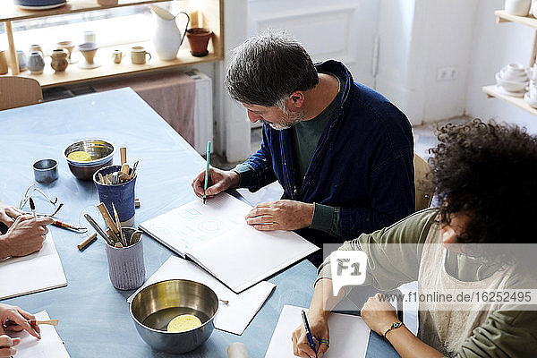 Hochwinkelansicht Mann und Frau beim Zeichnen am Tisch während des Kunstunterrichts