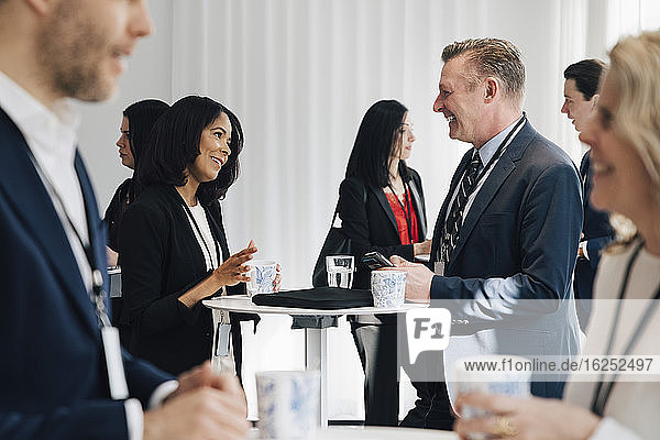 Smiling female entrepreneur talking to mature colleague at table in office seminar