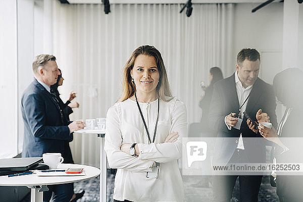 Portrait of confident businesswoman with arms crossed standing at workplace