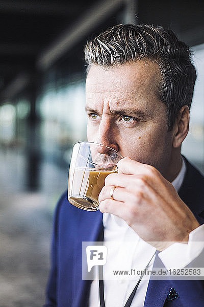 Geschäftsmann trinkt Tee  während er am Arbeitsplatz wegschaut