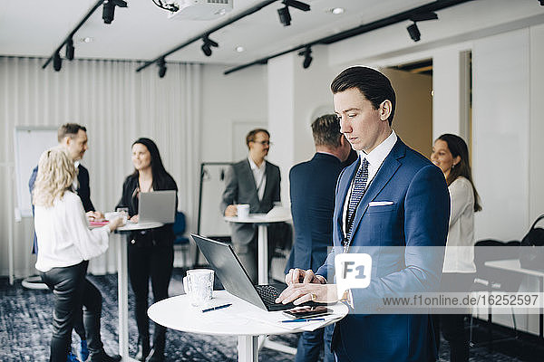 Businessman working over laptop while standing in office seminar