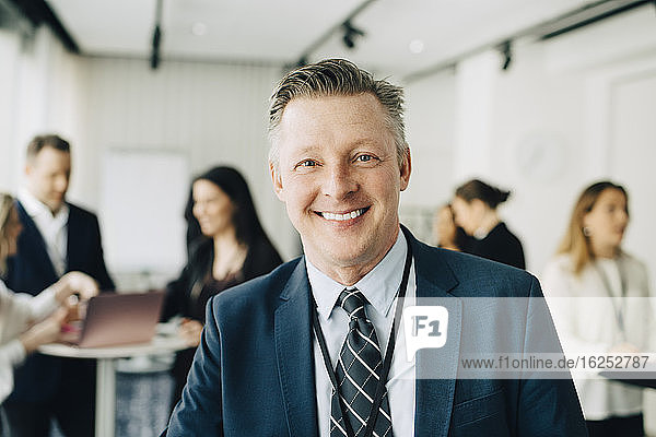 Porträt eines glücklichen Geschäftsmannes  der im Büroseminar steht
