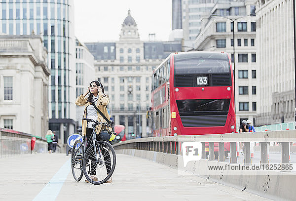 Geschäftsfrau mit Kopfhörern und Fahrrad auf der City Bridge  London  UK