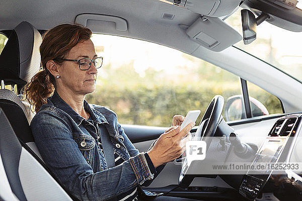 Reife Frau schreibt SMS  während sie im Auto sitzt