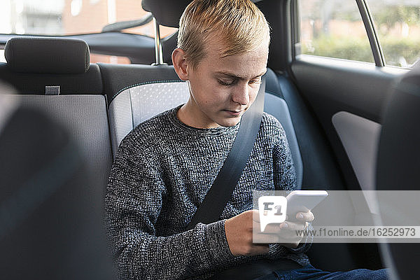Männlicher Teenager telefoniert  während er im Auto sitzt
