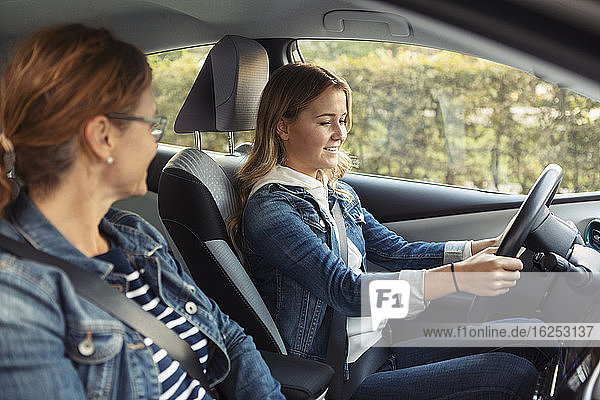 Mutter unterrichtet lächelndes Teenager-Mädchen beim Autofahren am Wochenende