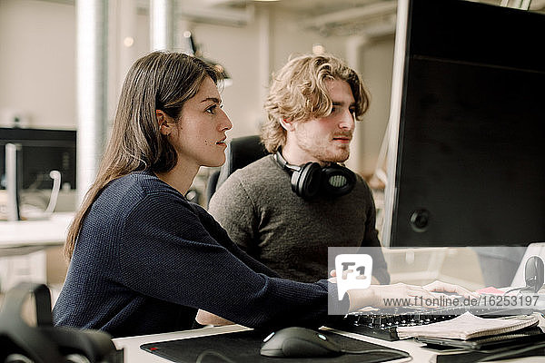 Side view of female entrepreneur working with coworker in office