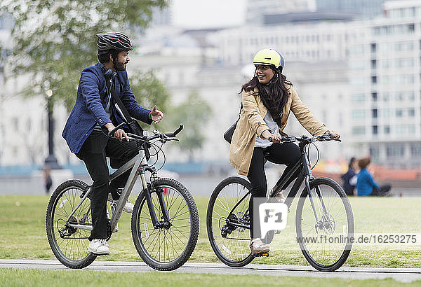 Geschäftsleute fahren Fahrrad und unterhalten sich im Stadtpark