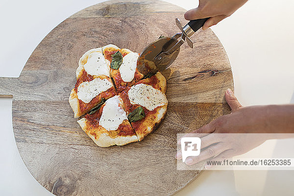 Frau schneidet frische hausgemachte Pizza auf Schneidebrett
