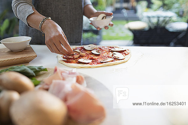 Frau macht selbstgemachte Pilz-Pizza