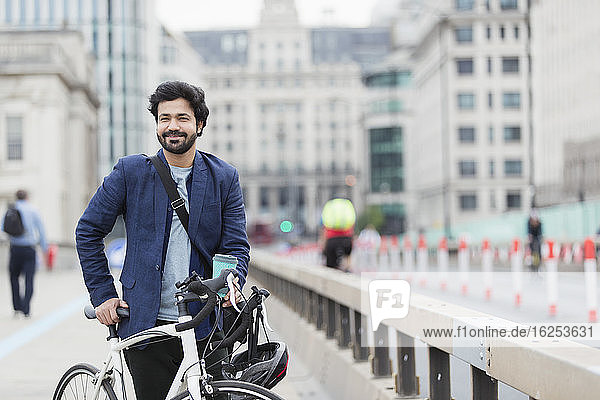 Porträt eines lächelnden Geschäftsmannes mit Fahrrad und Kaffee auf der Stadtbrücke