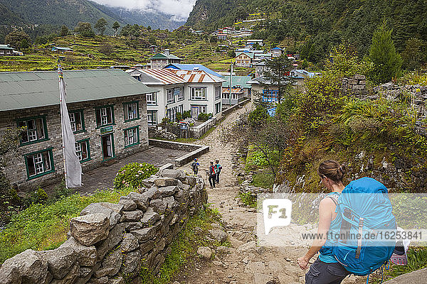 Eine Gruppe auf Rucksacktour durch eine Stadt in einem Tal des Himalaya; Nepal