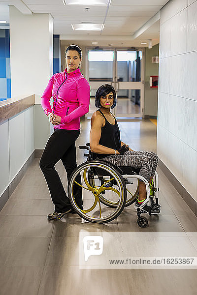 A paraplegic woman and her trainer pose for the camera while in a hallway in a recreational facility: Sherwood Park  Alberta  Canada