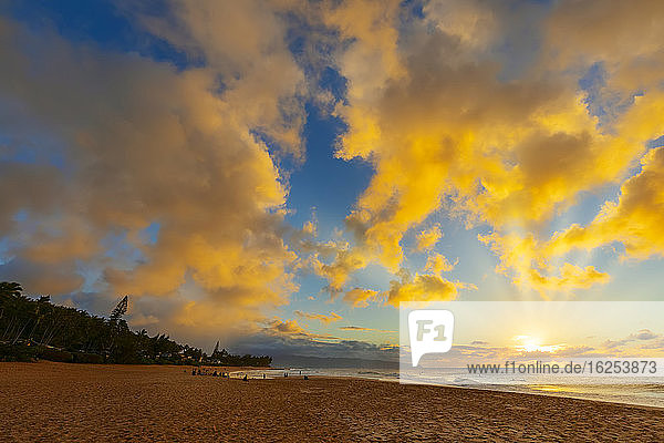 Silhouette von Surfern am Kelki Beach mit dramatisch leuchtenden Wolken darüber bei Sonnenuntergang; Oahu  Hawaii  Vereinigte Staaten von Amerika