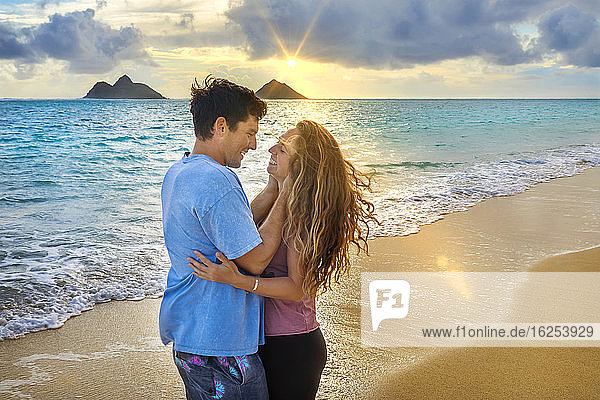A couple stands in an affectionate embrace on Lanakai beach on the Hawaiian island of Oahu at sunset; Lanakai  Oahu  Hawaii  United States of America