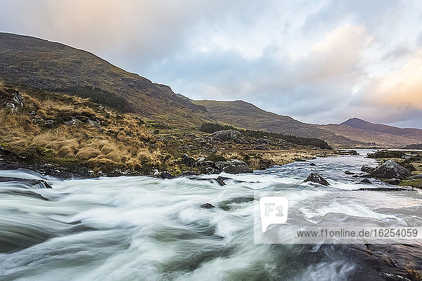 Cascades on a river in the Black Valley in Kerry with the MacGillycuddy's Reeks in the background on a cloudy day; County Kerry  Ireland
