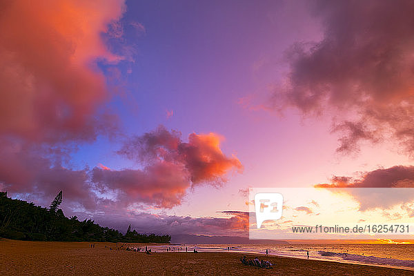Silhouette von Surfern die am Kelki Beach am Wasser stehen mit dramatisch leuchtenden Wolken darüber bei Sonnenuntergang; Oahu Hawaii Vereinigte Staaten von Amerika