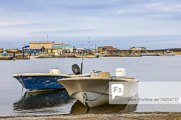 Fischerboote ankerten an einem Spätsommerabend im Schwanensee mit einigen Gebäuden in der Stadt und Booten auf der anderen Seite des Sees; Kotzebue  Alaska  Vereinigte Staaten von Amerika