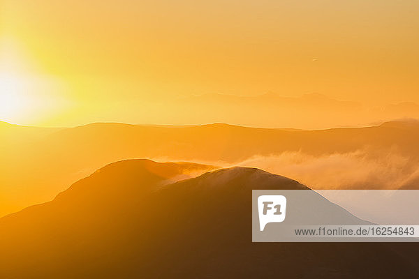 Silhouette eines Hügels in Kerry bei Sonnenaufgang mit Schneeverwehungen von der Spitze MacGillycuddy's Reeks; Grafschaft Kerry Irland