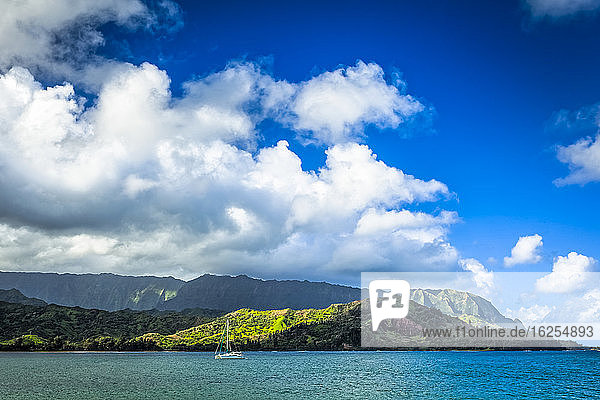 Hanalei Bay with lush green mountains in background under blue sky; Hanalei Bay  Kauai  Hawaii  United States of America