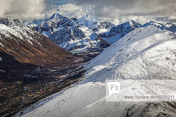 Snowy Rendezvous Ridge and Cantana Peak above Eagle Lake. Fall coloured South Fork Eagle River Valley below the mountains. Chugach State Park  South-central Alaska in autumn; Anchorage  Alaska  United States of America