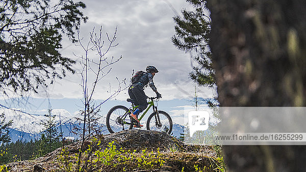 Woman mountain-biking in a forest in the Canadian mountains