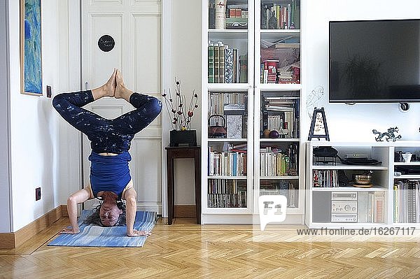 Ältere Frau bei einer Yoga-Sitzung in ihrem Wohnzimmer in Madrid (Spanien)