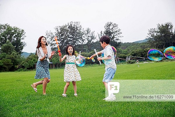 Mutter mit zwei Kindern  die auf dem Rasen spielen