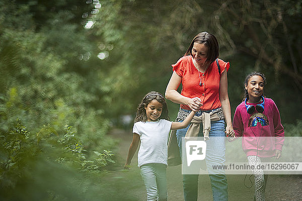 Mother and daughters hiking on trail in woods