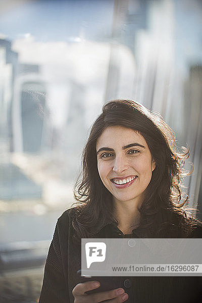 Portrait confident smiling businesswoman with smart phone