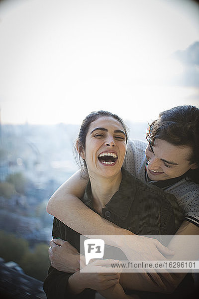Glückliches junges Paar lacht und umarmt sich auf dem Balkon