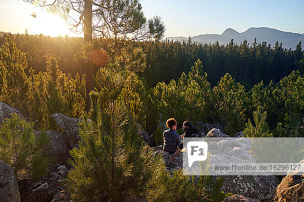 Young hiking couple relaxing on rock in sunny scenic woods