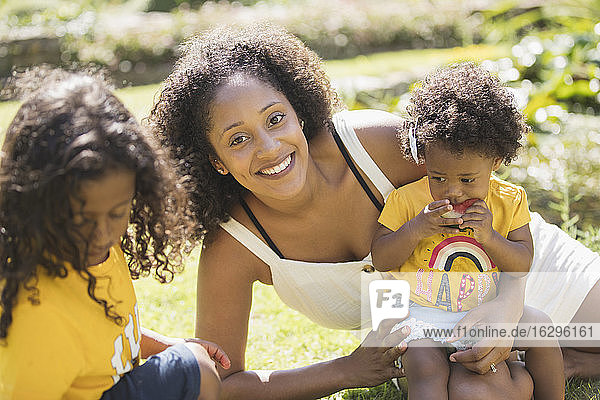 Portrait glückliche Mutter und Kinder im sonnigen Sommerhof