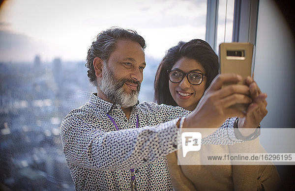 Business people taking selfie at highrise office window