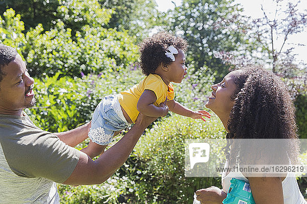 Liebevolle Eltern und Kleinkind-Tochter im sonnigen Sommergarten