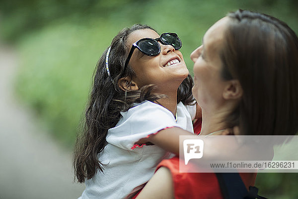 Glückliche Mutter hält Tochter mit Sonnenbrille