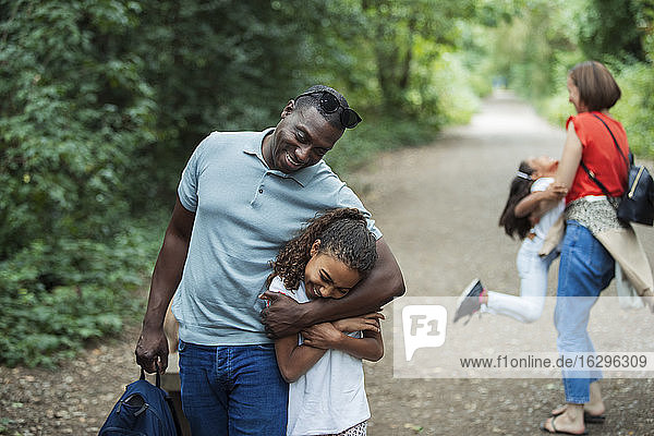 Glücklicher Vater und Tochter umarmen sich auf dem Parkpfad