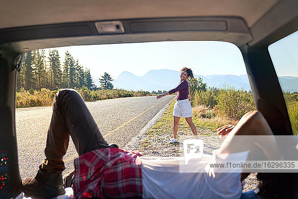 Happy carefree couple relaxing outside car at sunny remote roadside